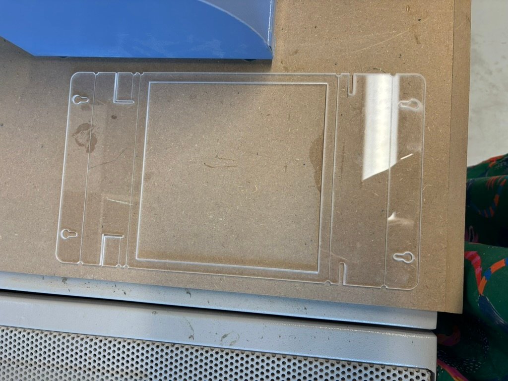 Image of a clear perspex sheet of plastic which has been laser cut and currently flat